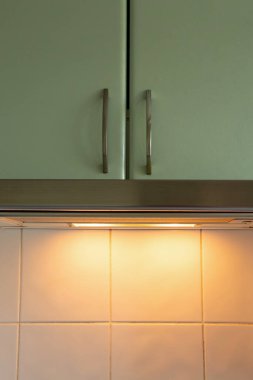 Kapüşonlu ve yeşil cepheli modern mutfak mobilyaları beyaz fayanslar üzerinde bir apartman dairesinde, evde mutfak