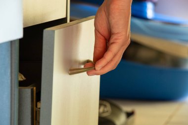 Kadın eli ev ortamında dolap çekmecesini açıyor, dairede mobilya var.