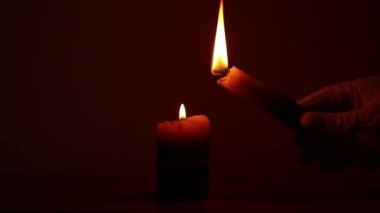 Eldivenli el, karanlıkta başka bir mum alevinden mum yakar, mum ışığı, yanan mum.