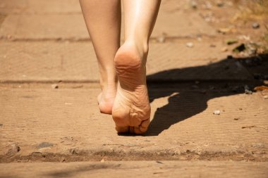 Güneşin altında yol boyunca yürüyen kadınların yalın ayakları - yolun, hareketin, seçimin ve yaşamın bir sembolü