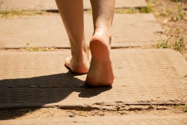 Güneşin altında yol boyunca yürüyen kadınların yalın ayakları - yolun, hareketin, seçimin ve yaşamın bir sembolü