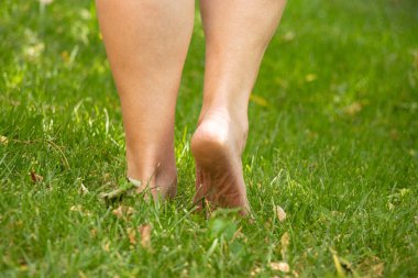 Yazın Ukrayna 'da bir parkta çimlerin üzerinde çıplak ayaklı yaşlı bir kadın.