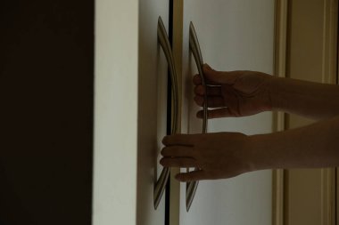 Koridordaki beyaz dolabın kapı kolundaki kadın, ev mobilyası.