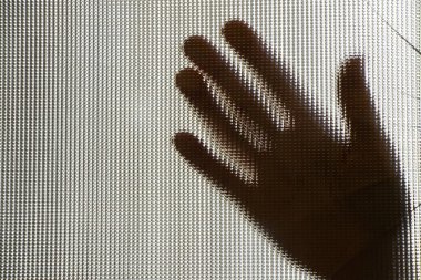 Yakın plan çekimleri için kırık bir camın arkasında bir kadının elinin silüeti.