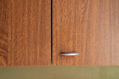 Kapalı ahşap mutfak kapıları, metal sapları, koyu ahşap dokusu, modern mutfak iç mimarisi.