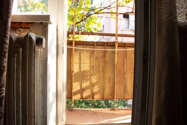 Yatak odasının penceresinin yanındaki eski dökme demir kalorifer, açık bir balkon ve Ukrayna 'da bir apartman dairesinin ön cephesi...