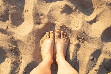 Güneşli bir yaz günü Ukrayna 'da nehrin kıyısındaki kumların üzerinde çıplak ayakla duran kadınlar.