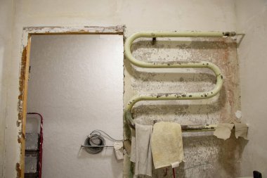 Tadilat sırasında banyo, eski metal ısıtmalı havlu tırabzanı, soyulmuş boya, bitmeyen kapı, apartmanın koridoru.