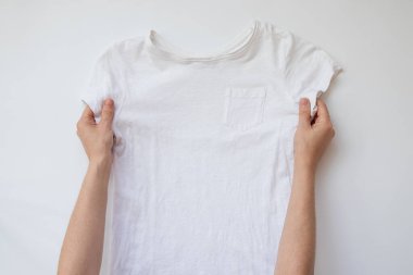 Beyaz arkaplan üzerinde kısa kollu beyaz tişört tutan kadın elleri model veya şablon için