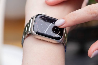 Ukrayna Krivoy Rog 08 / 23 / 2025 - ekranda gösterilen saat, tarih, hava ve pil eşliğinde bir Apple Saat 9 akıllı saat takan bir kadının yakın çekimi