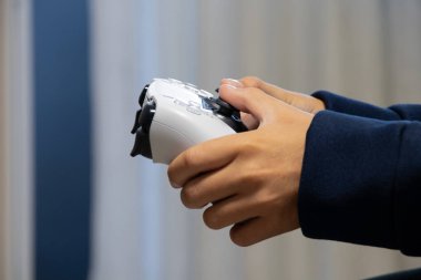 Çocuk TV 'nin yanında oturmuş elinde beyaz joystick ile video oyunu oynuyor, bilgisayar oyunları oynuyor