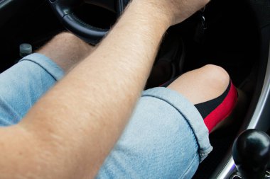 Kırmızı ve siyah tedavi bantlı erkek diz eklemi desteklemek için uygulanır, yolda araba sürerken kan dolaşımını hızlandırır.