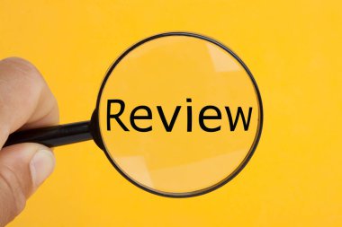 Hand holding magnifying glass over the word review. clipart