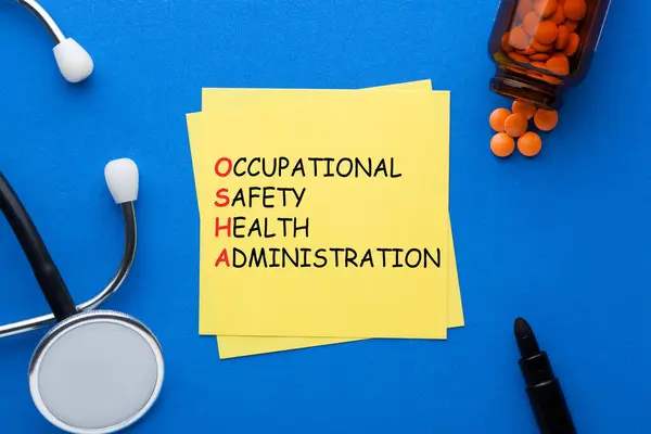 OSHA - Occupational Safety and Health Administration acronym written on note with stethoscope, pills and various stationery.