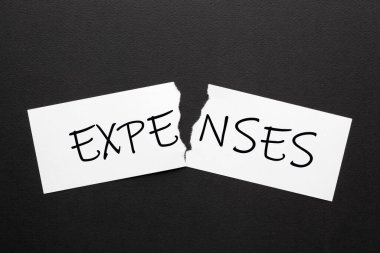 Siyah arka planda yırtık kağıt üzerindeki harcamalar. Mali konsept