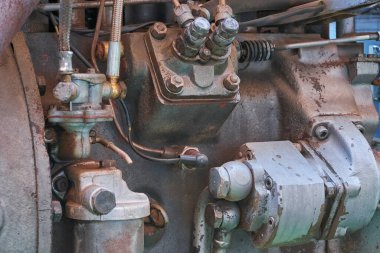 Yıpranmış bir endüstriyel motorun yakın çekimi çeşitli metalik doku ve tonlara sahip kirli mekanik parçalar, borular ve cıvatalar sergiliyor..