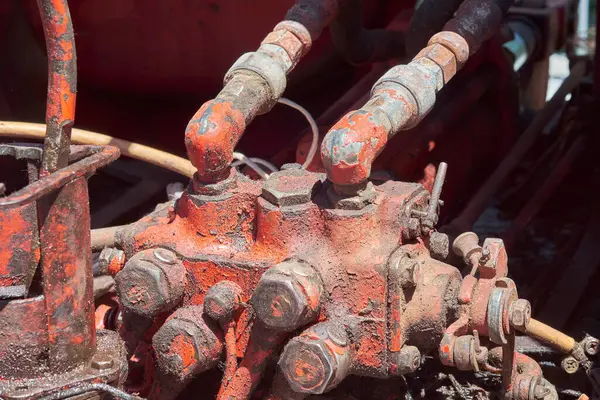 Ağır paslanmış ve yıpranmış hidrolik hatlar ve endüstriyel bir makinedeki kontrol vanaları, eski metalin kumlu dokusunu ve kullanılmış görünümü sergiliyor..