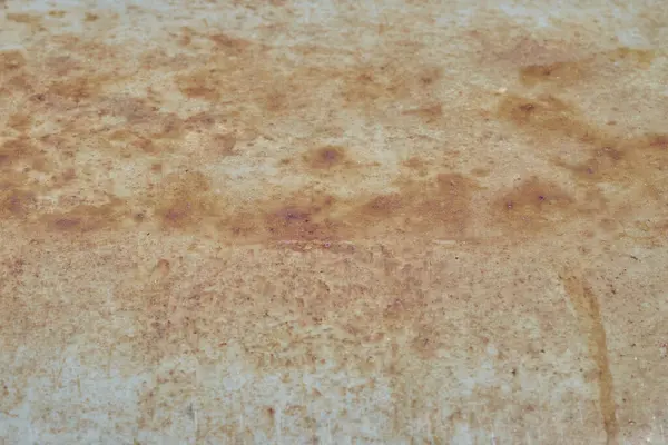 Yıpranmış metal bir yüzeye yakın çekim geniş turuncu ve kahverengi pas altında solmuş açık mavi boya karışımını göstererek soyut ve sıkıntılı bir doku oluşturur..