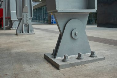 Sağlam çelik destek kirişine yakın çekim. Beton bir zemine demirlenmiş. Endüstriyel dayanıklılık ve modern yapı tasarımı sergiliyor..