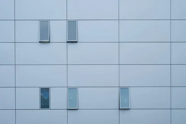 Izgara desenli ve minimalist pencereli çağdaş bir bina cephesinin soyut görünümü.