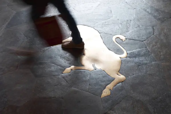 Torino 'nun karanlık kaldırımına gömülü ikonik pirinç boğa. Bulanık bir insanın bacakları ve gölgesi üzerinden geçerek şans ve geleneği simgeliyor..