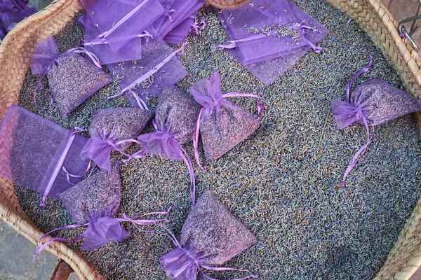 Mor organza kesesinde hasır sepette sergilenen lavanta tomurcukları. Çekmeceler, dolaplar ve rahatlama için doğal, el yapımı koku torbaları..
