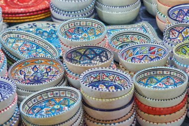 Geleneksel bir pazarda, karmaşık desenli, el yapımı seramik kaselerin canlı görüntüsü. Kültürel işçiliğin ve sanatsal tasarımın mükemmel bir temsili..