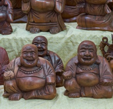 Kumaşa dizilmiş el oyması, ahşap, gülen Buda heykelleri. Mutluluğun sembolü, refah ve Asya kültürlerinde iyi şanslar. Manevi veya dekoratif temalar için ideal.