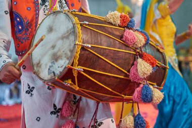 Kültür festivalinde canlı bir Bhangra dansı sırasında geleneksel Punjabili bir sanatçı tarafından çalınan süslü bir dhol davulunun yakın çekimi..