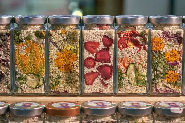 Kurutulmuş sebze, meyve, çiçek ve pirinçle dolu cam kavanozlar. Gurme kullanımı veya dekoratif amaçlar için doğal malzemelerin canlı ve sanatsal bir gösterimi.