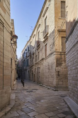 Yıpranmış kireçtaşı cepheleri, işlenmiş demir balkonları ve İtalyan tarihi merkezinde geleneksel taş kaldırımları olan dar bir ortaçağ sokağı.