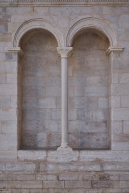 Dekoratif sermayeyle oyulmuş taş sütunlarla ayrılmış çift yuvarlak kemerler. Kireçtaşındaki klasik Romanca mimari detay.