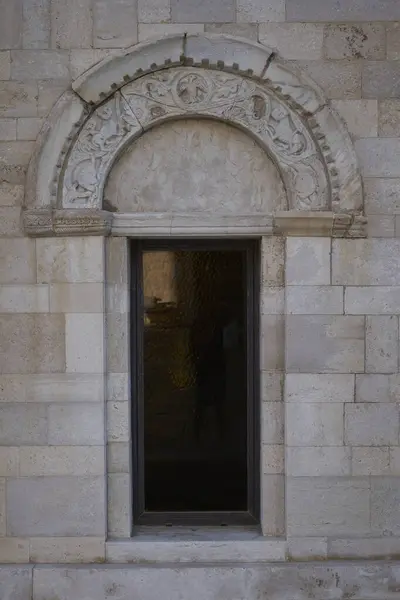 Karmaşık dini heykeller ve süs kemerleriyle oyulmuş antik taş kapı. Timpanum sanatıyla ortaçağ kilisesi girişi.