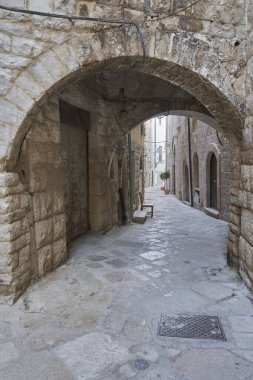 Charming stone archway leading to a narrow alley in a historic European town, medieval street architecture background