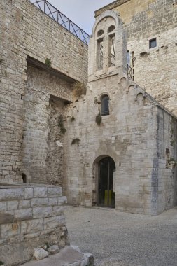 Old stone chapel with arched doorway and bell tower, medieval religious architecture within a historic European fortress