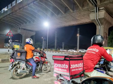Delhi, Hindistan - 2022 dolaylarında: Zomato bisikletli kurye teslimatçı çocuk Swiggy Food Tech starup uygulamalarından yarışma ve Hindistan 'daki bu oyuncular arasında geçiş olduğunu gösteriyor