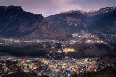 aerial drone shot of manali hill station blue hour evening with building lights at dusk showing valley with fog covered himalaya mountains showing tourist spot in himachal India