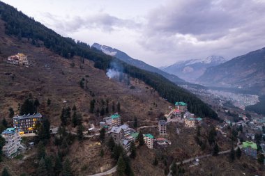 aerial drone landing shot showing lit multi floor story buildings on side of hill at night evening showing hotels shopping areas in manali, shimla himachal India