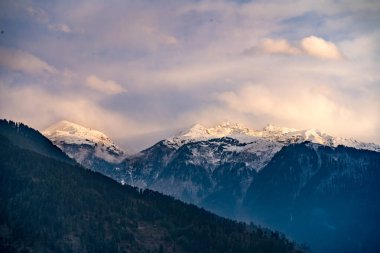Muson bulutları kar üzerinde ilerlerken Himalaya dağlarını kapladı. Mavi turuncu günbatımı gündoğumu ışığı Kelemeli Manali Vadisi Hindistan 'ın üzerindeydi.