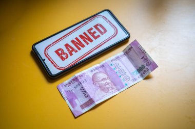 Hindistan 'da yasaklanmış çağrıyı gösteren cep telefonuyla sarı masadaki gösterim yoluyla sirkülasyondan kaldırılan 2000 rupilik Hint banknotu.
