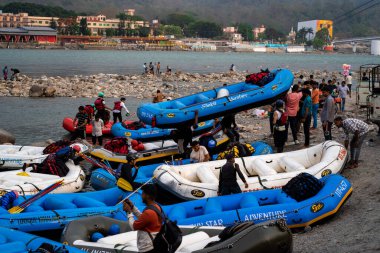 Rishikesh, Haridwar, Hindistan - 2023 dolaylarında, macera sporunun bittiği sahilde şişme beyaz su salları bir sonraki sefer için insanların salları ve kürekleri götürmesiyle son buluyor.