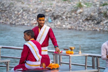 Rishikesh, Uttarakhand - 2023 dolaylarında: Bir grup rahip akşam ganga aarti törenine hazırlanıyor ve planı kırmızı üzerine beyaz giyen guru öğretmenleriyle tartışıyor