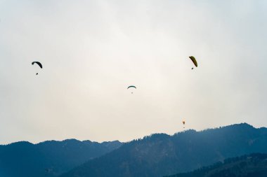 Günbatımı gökyüzüne ve dağlara karşı paraşütçü uçakları çoğalt. Kopya alanı ve parlak renklerle Hindistan 'daki tepe istasyonunda özgürlüğü göster.