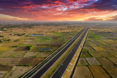 Yeni Delhi Mumbai Jaipur ekspres otoyolunun kenarı dikdörtgen çiftlikleri olan yeşil kuyruklu altı şeritli üç ayaklı hava aracı görüntüsü.