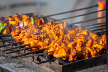 Isı sisi, duman ve tereyağı damlayan tereyağlı kebap içerken bir aşçı arka planda tavuk ve koyun etini gösterirken
