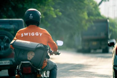 Bangalore, Hindistan - 7 Ekim 2023: Swiggy food dağıtım teknolojisi başlangıç teknolojisi Gün doğumunda kurye sürüşü bu iş işçilerinin uzun çalışma saatlerini gösteriyor