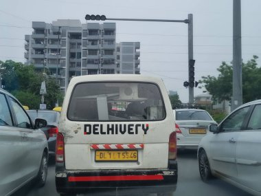 Delhi, Hindistan - 19 Ağustos 2023: Beyaz minibüs Hint lojistik şirketi Delhivery için son mil teslimatını gösteriyor.