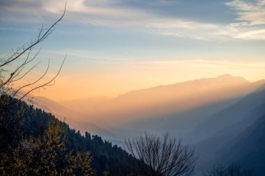 Himalaya dağlarının sakin manzarası Hamta köyü yürüyüşünden alacakaranlıkta güneş ışınlarının Hindistan 'daki Manali dağlarının arasından geçişini gösteriyor.