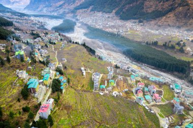 Hava aracı görüntüsü vadideki manali kullu kasabayı sisle kaplı himalaya dağları ve Hindistan 'daki tepe istasyonlarının güzelliğini gösteren yeşil alanlar arasında gösteriyor.