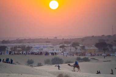 Hindistan 'da popüler bir turistik faaliyet gösteren Jaisalmer Rajasthan' da gün batımında turist taşıyan develer.